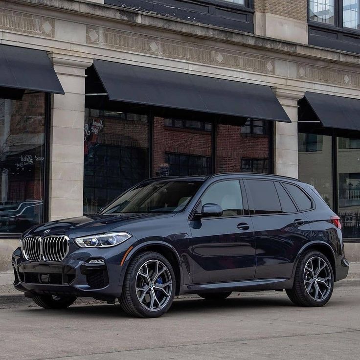 the new bmw x5 suv is parked in front of a building