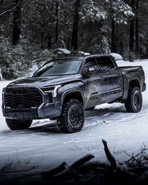 a black truck is driving through the snow