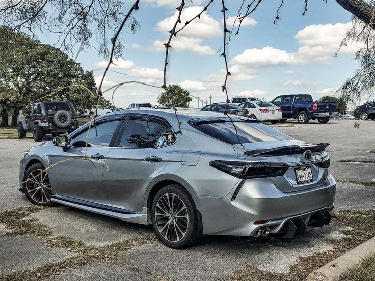 a silver car parked in a parking lot next to other cars on the side of the road