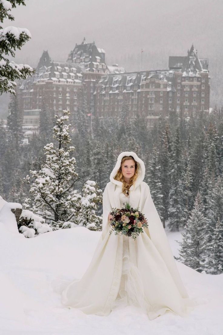 a woman in a white wedding dress standing on top of snow covered ground