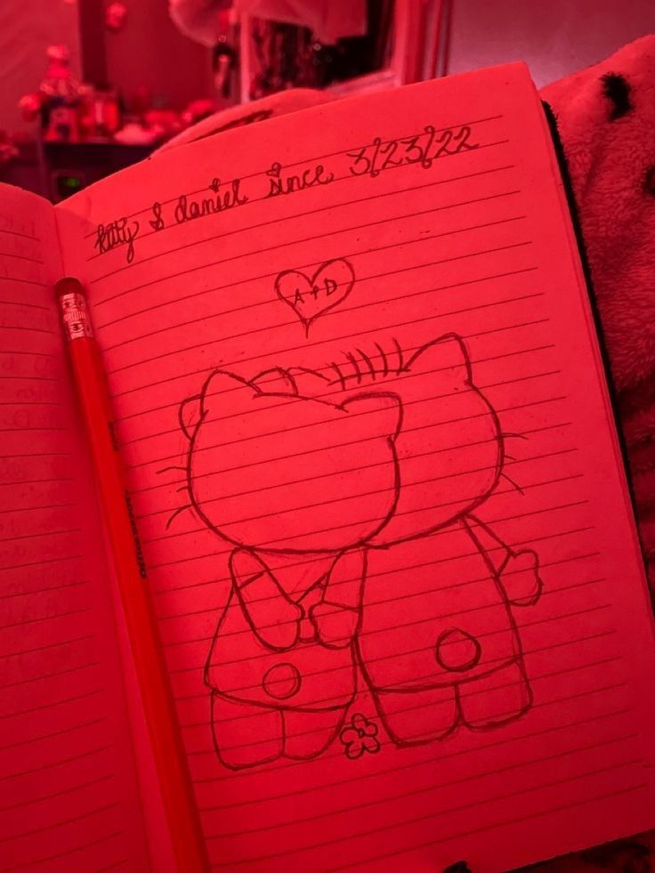 an open notebook with a drawing of a teddy bear and heart on the pages in red light