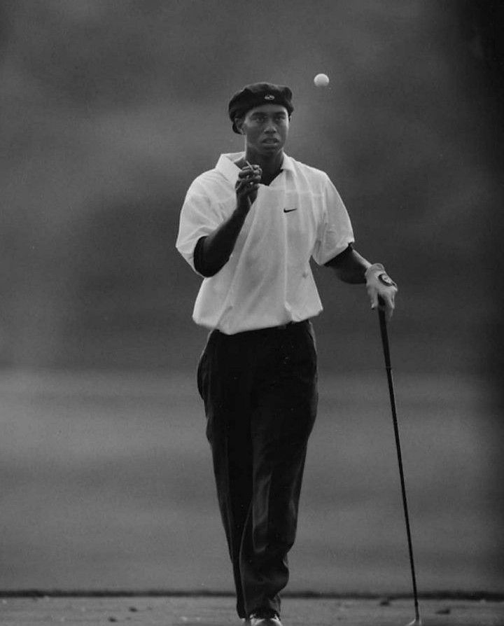 a black and white photo of a man hitting a ball with a golf club in his hand