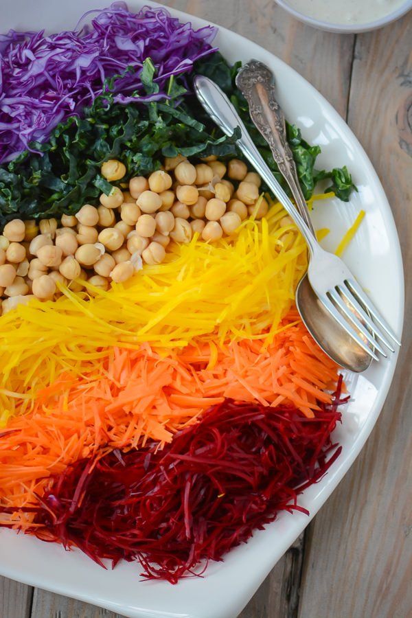 a white plate topped with different colored veggies next to a fork and knife