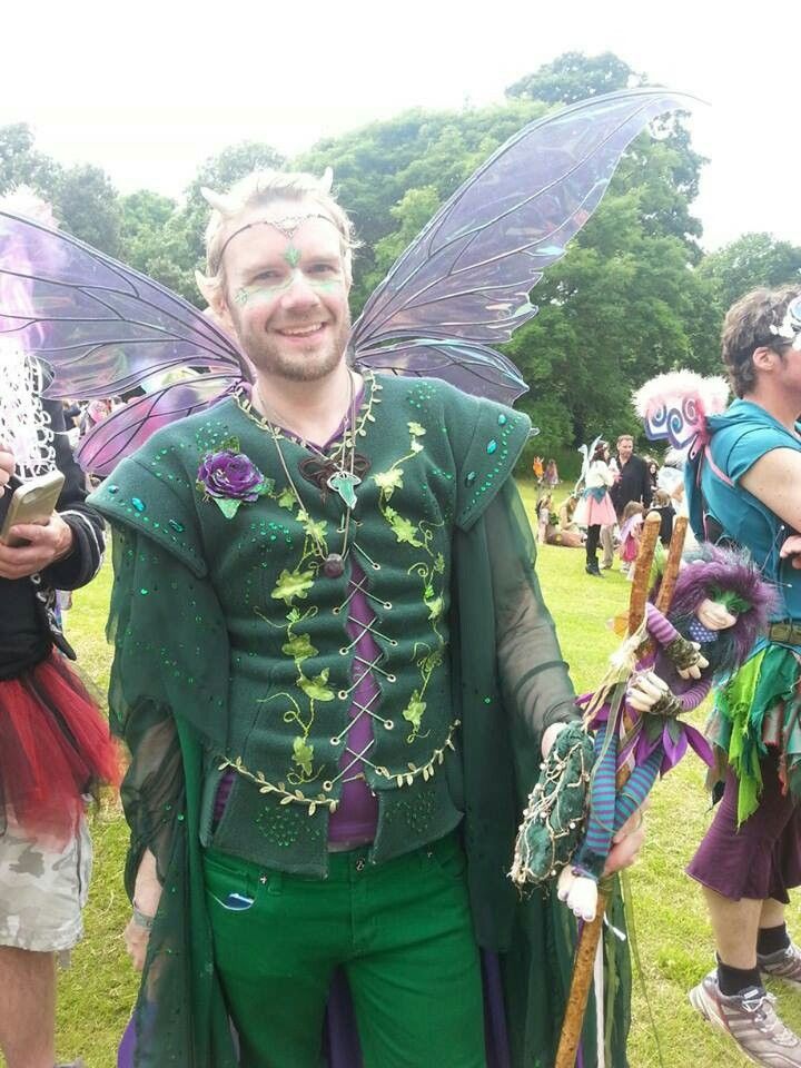 a man dressed up as tinkerbell and holding a stick in his hand while standing next to other people