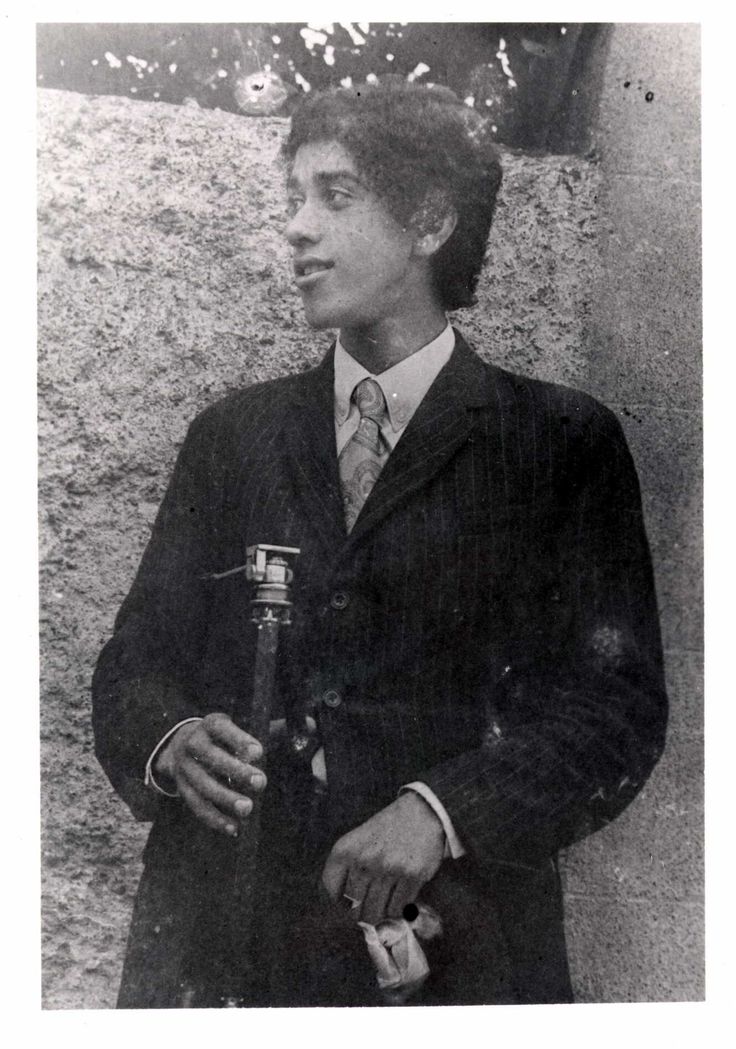 an old photo of a man in a suit and tie holding a bottle with something in it