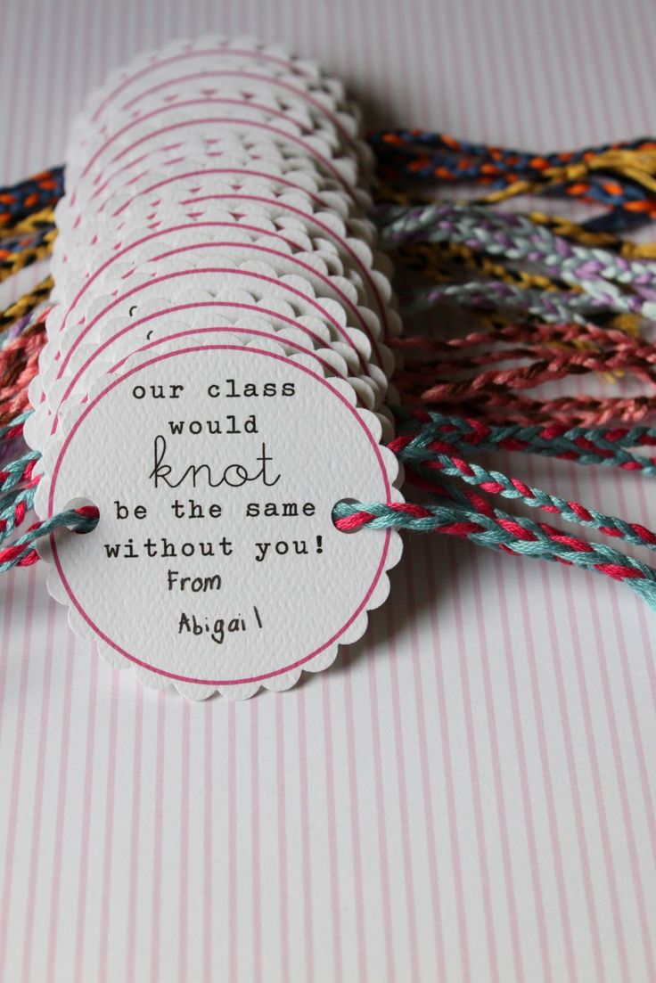 some paper tags with words on them sitting on a striped table cloth surface and tied to twine