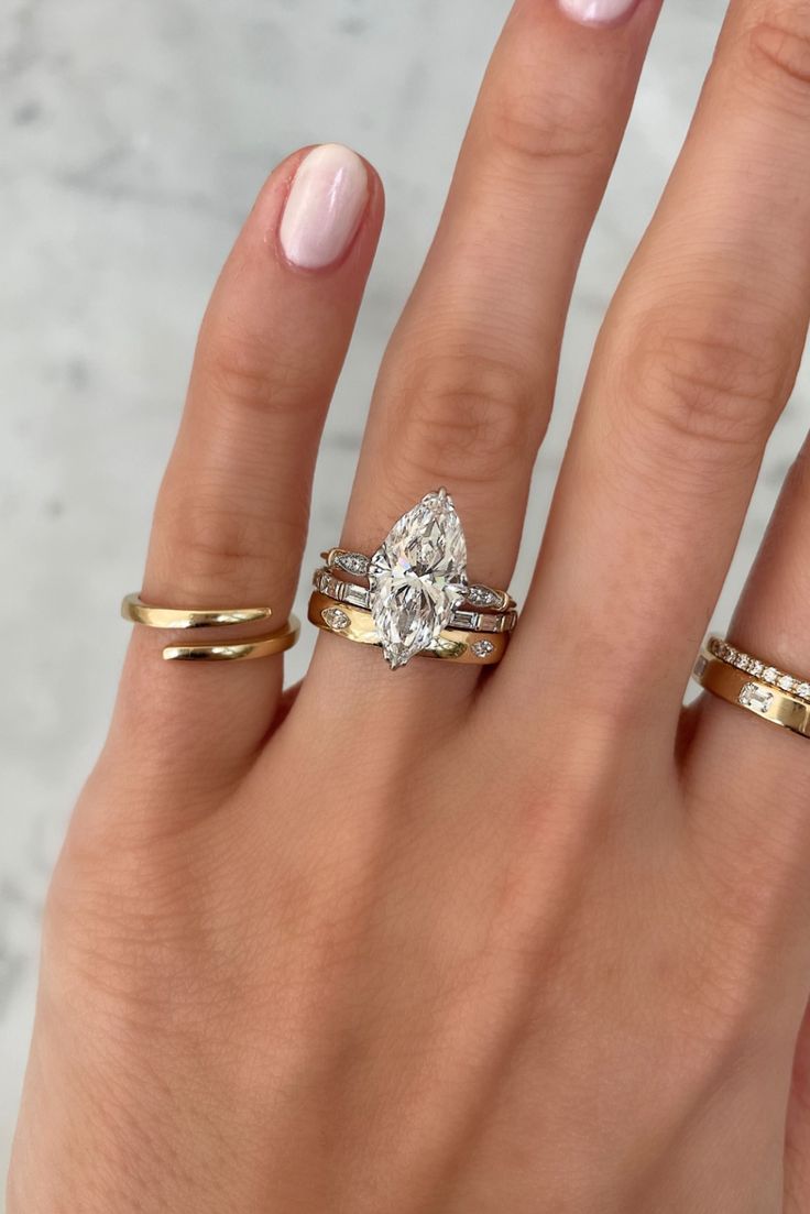 a woman's hand with three different rings on her fingers and one ring in the middle