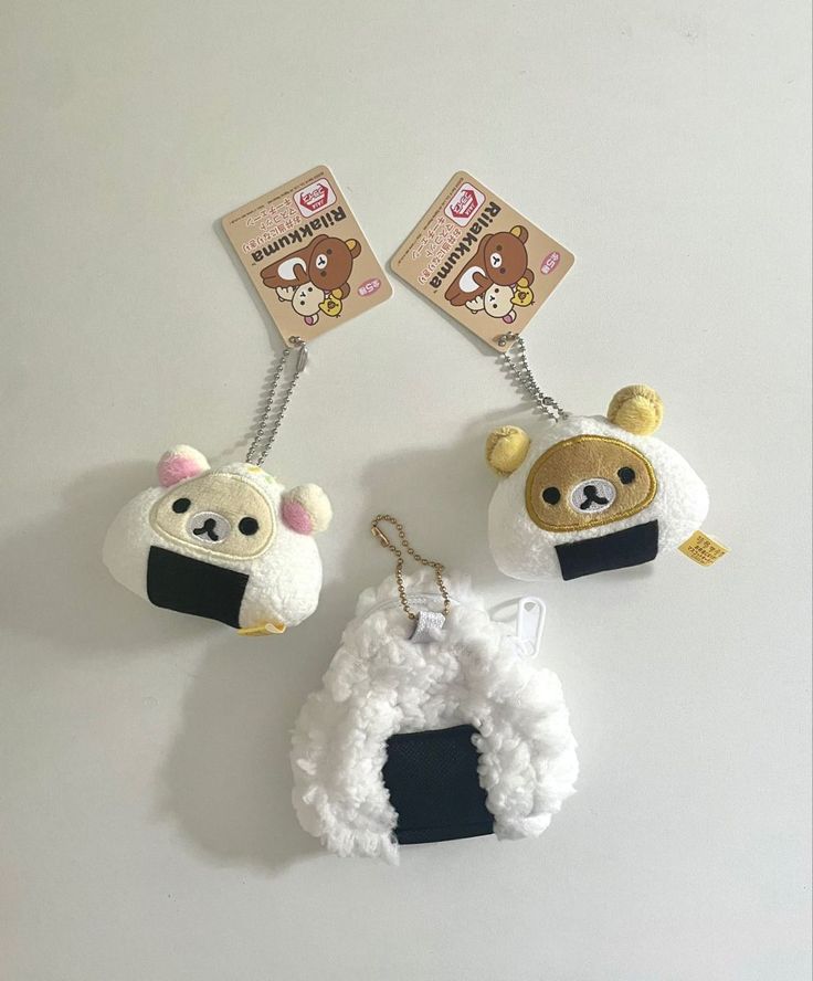 three keychains with animals on them hanging from the hooks in front of a white wall