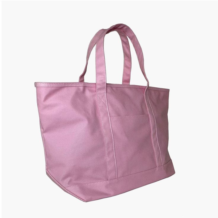 a pink tote bag is shown against a white background, with the handles folded down