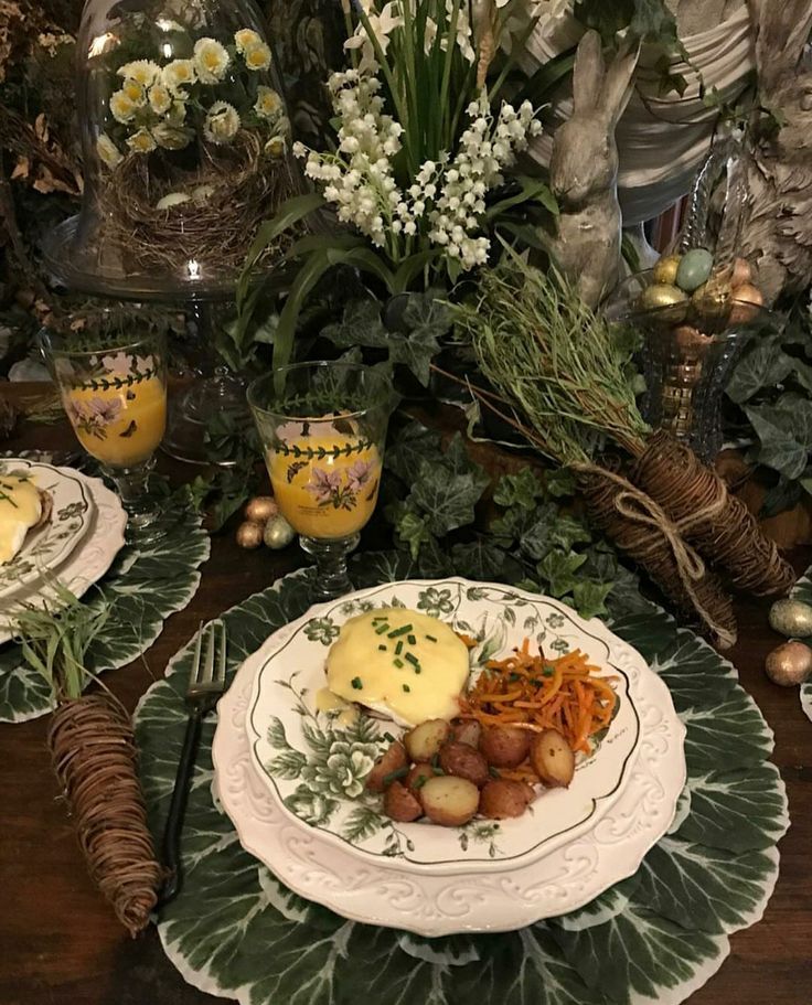 a table topped with plates filled with food and flowers on top of each plate covered in greenery