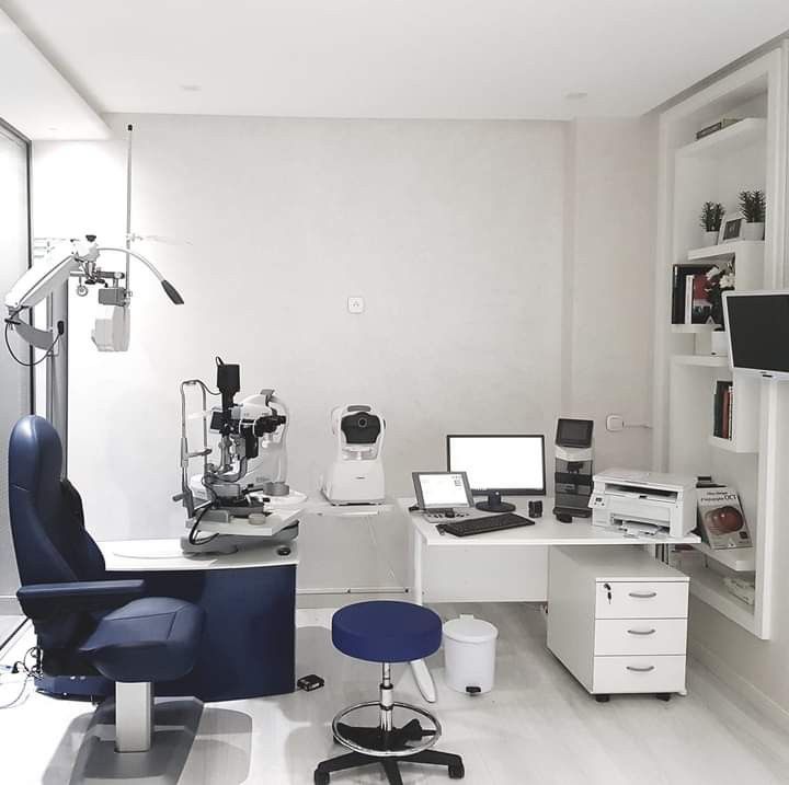 an office with white walls and blue chair in the center, computer desk on top of it