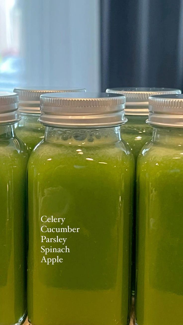 four jars filled with green liquid sitting on top of a table