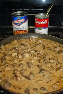 a pan filled with food sitting on top of a stove next to cans of soup