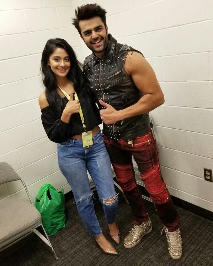 a man and woman standing next to each other in front of a white brick wall