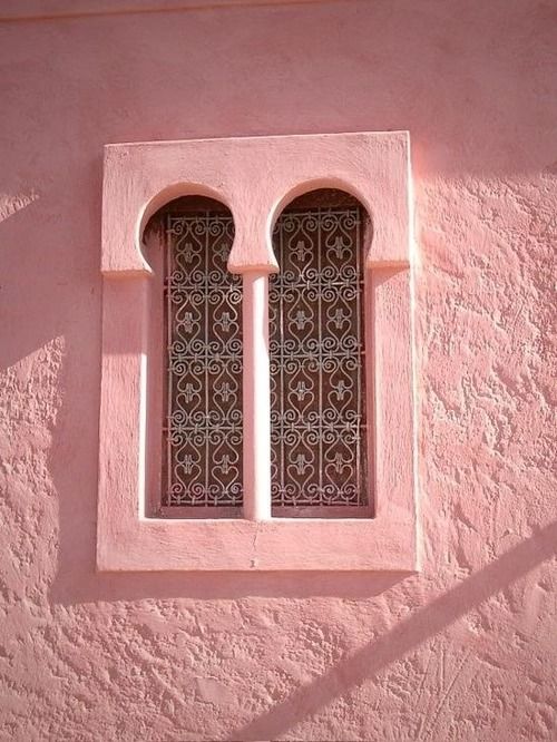 a pink building with two arched windows on the side and one window in the middle