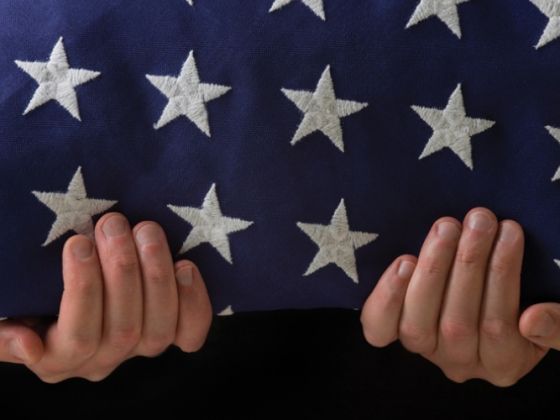 two hands holding an american flag with white stars on it's fabric covering the entire body