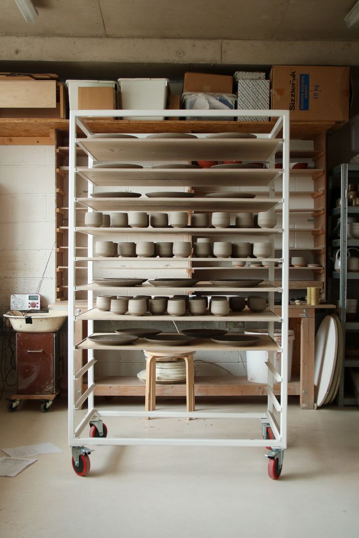 the shelves are full of bowls and plates on casteors in this room with no one around them