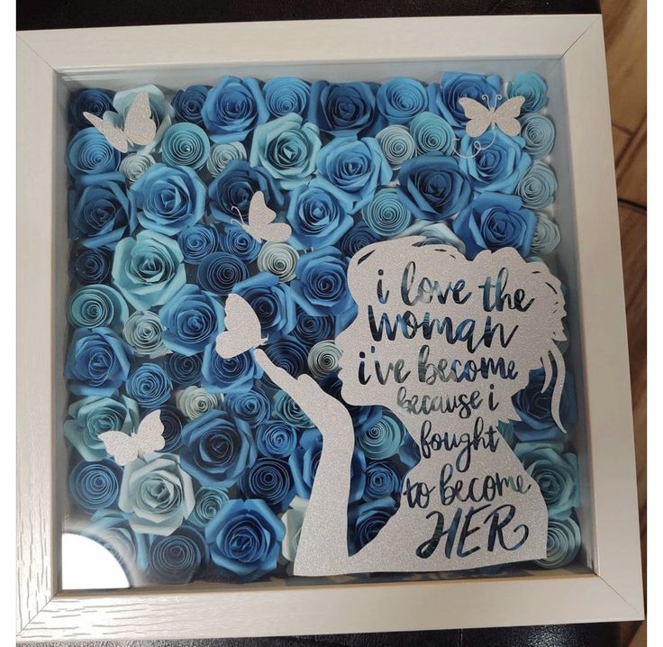 a framed paper art with blue roses and a silhouette of a woman holding a butterfly