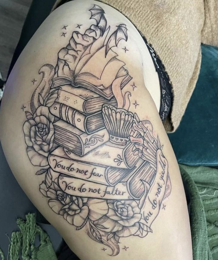 a woman's thigh with books and roses on it