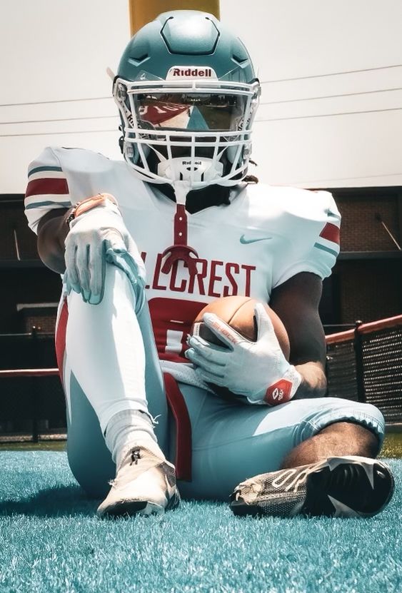 a football player sitting on the ground holding a ball