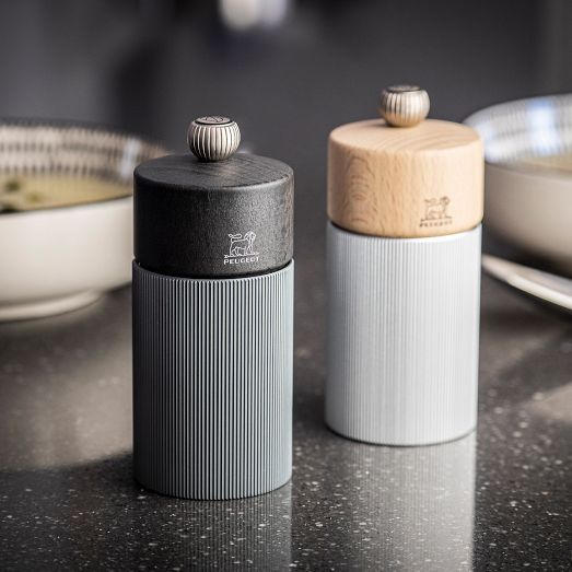 two salt and pepper shakers sitting on top of a counter next to a bowl