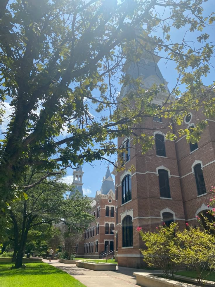 the sun shines brightly on an old brick building with a steeple in the background