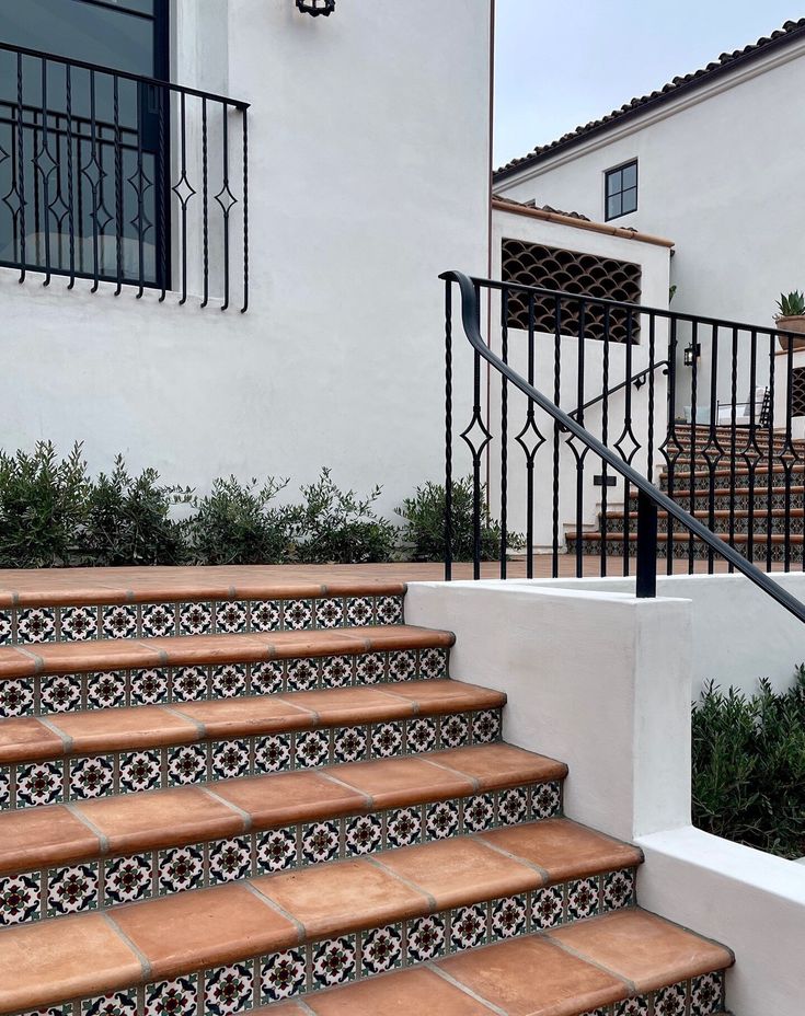 an outdoor stair case with decorative tiles and wrought iron railing