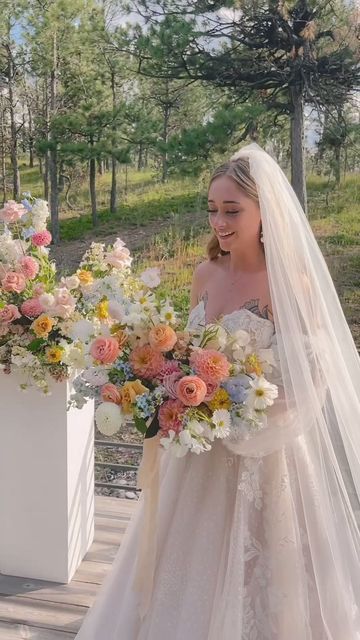 a woman in a wedding dress is holding a bouquet and standing on a wooden platform