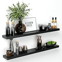 two black shelves filled with bottles and glasses on top of each other next to a potted plant