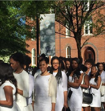 a group of women standing next to each other in front of a building on a sunny day