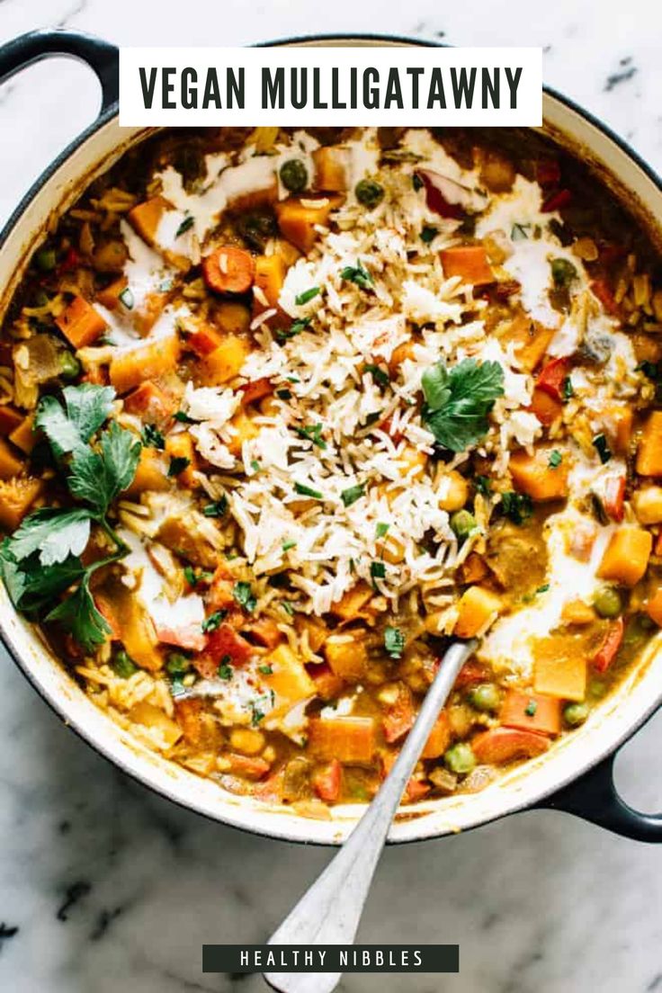 a pot filled with rice and vegetables on top of a white countertop next to a spoon