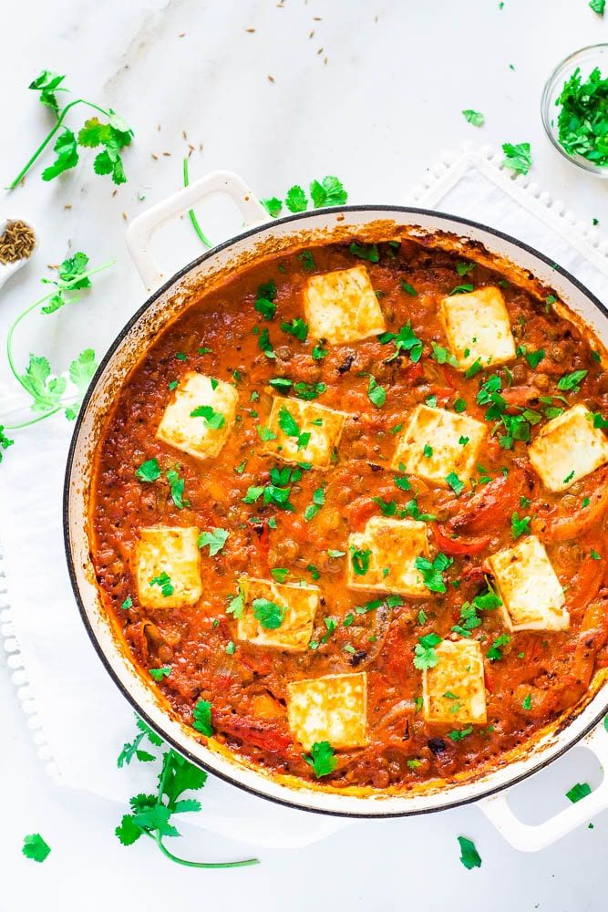 a pot filled with tofu and sauce on top of a white cloth next to some parsley