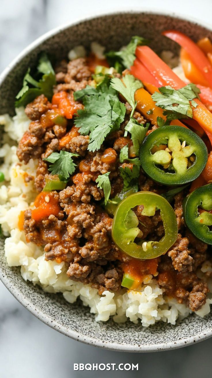 a close up of a bowl of food with rice and peppers on the side,