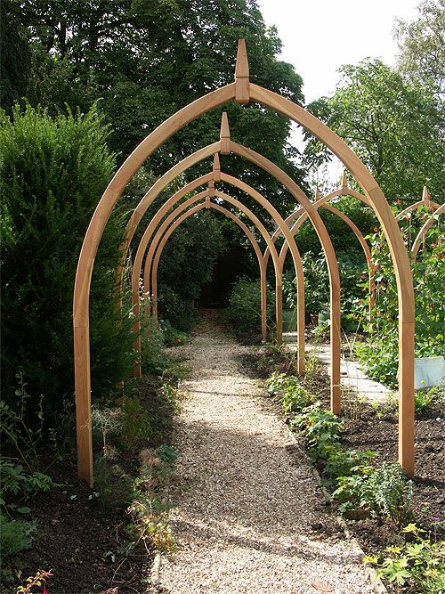 a wooden arch in the middle of a garden