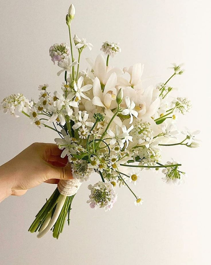 a hand holding a bouquet of white flowers