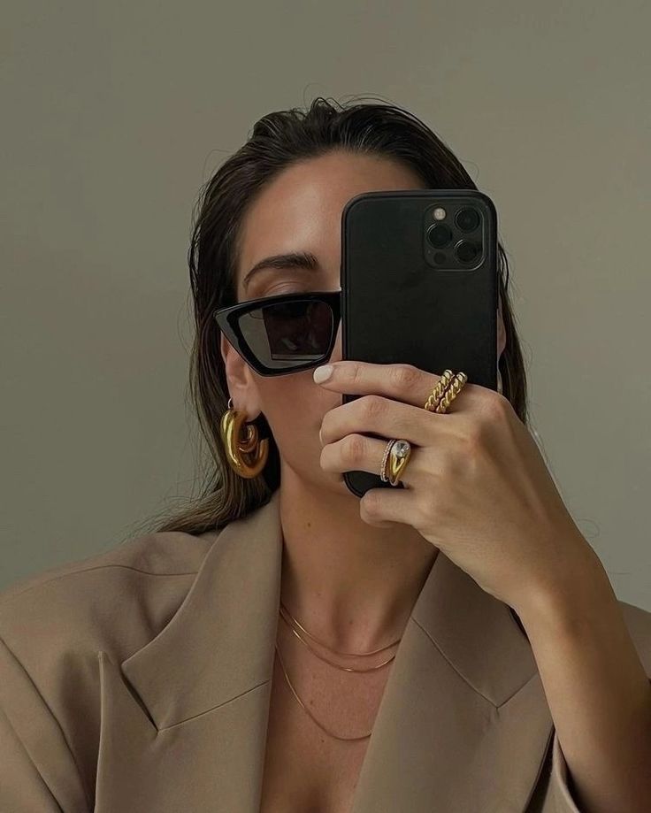 a woman taking a selfie with her cell phone in front of her earring