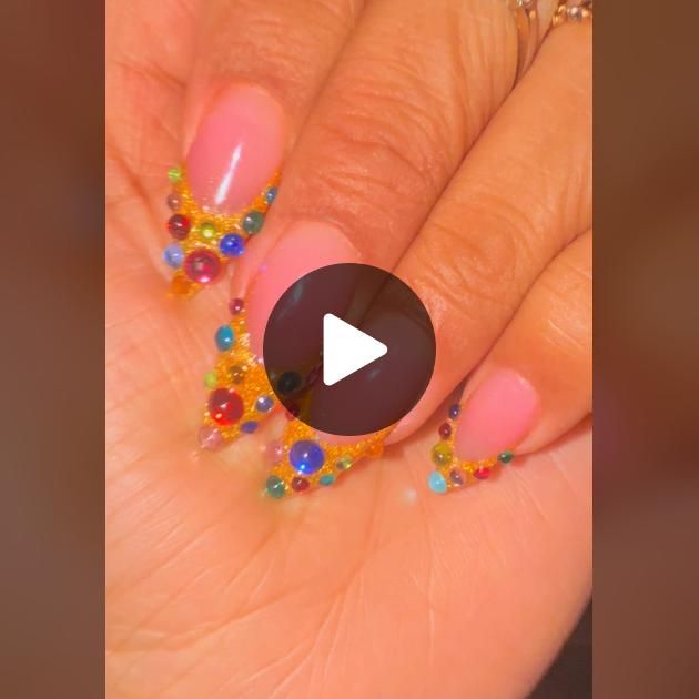 a woman's hand with colorful beads on it and a video screen showing how to do nail art