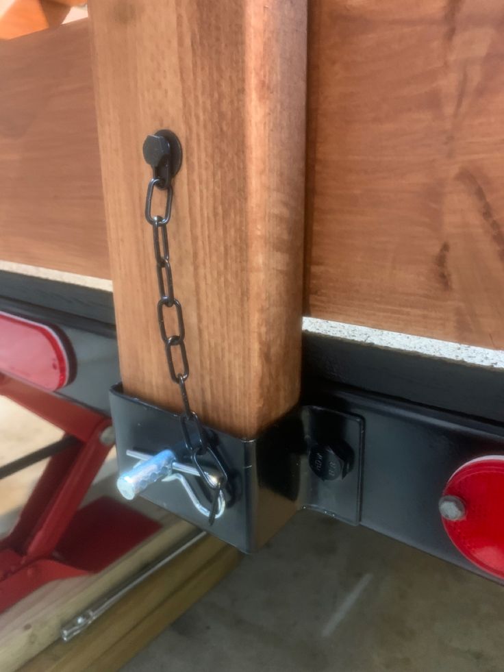 a close up of a wooden door with a chain on the bottom and red handles