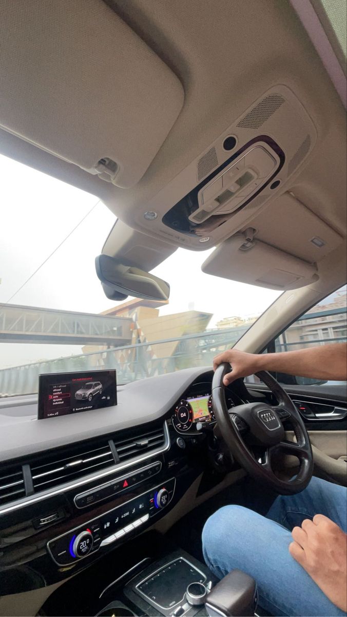 a man driving a car with his hands on the steering wheel and other electronic devices