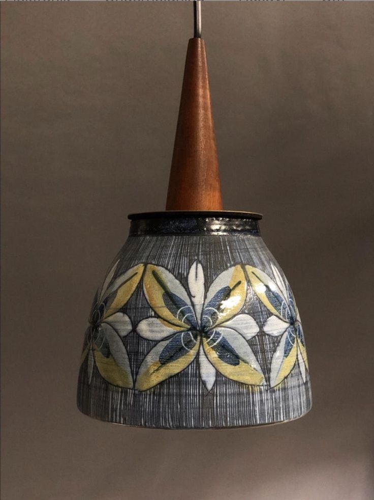 a blue and yellow lamp hanging from a wooden ceiling fixture with an orange cone on top