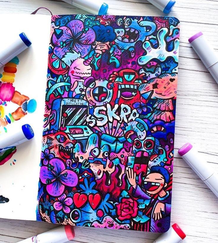 a notebook covered in lots of colorful doodles next to markers and crayons