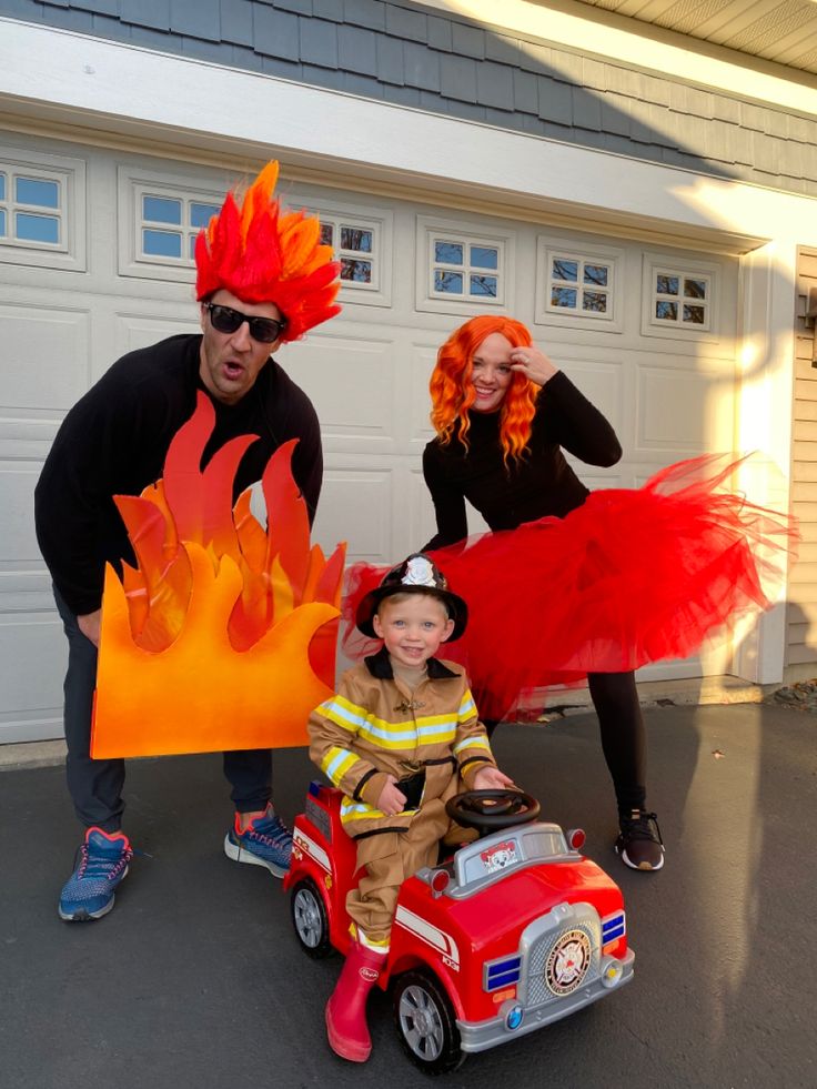 two adults and a child dressed up as fireman and woman with car costume in front of garage