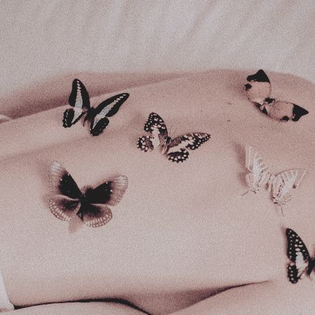 a woman laying on top of a bed with lots of butterflies flying over her stomach