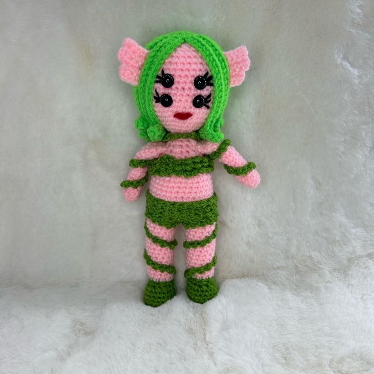 a crocheted doll with green and pink hair on a white background in the shape of an elf