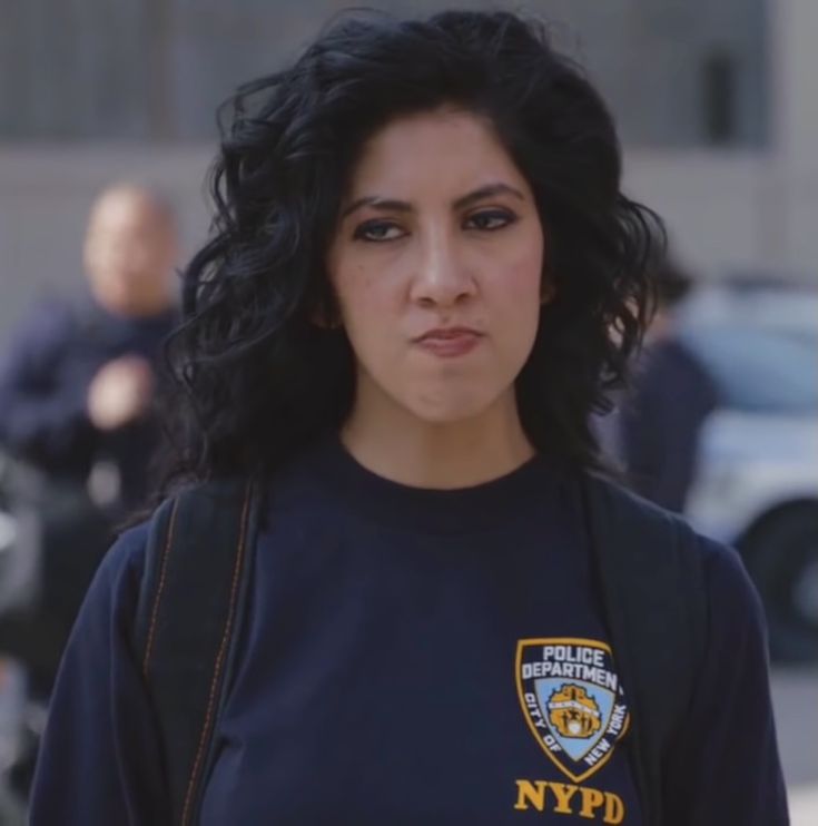 a woman with long black hair wearing a nypd shirt