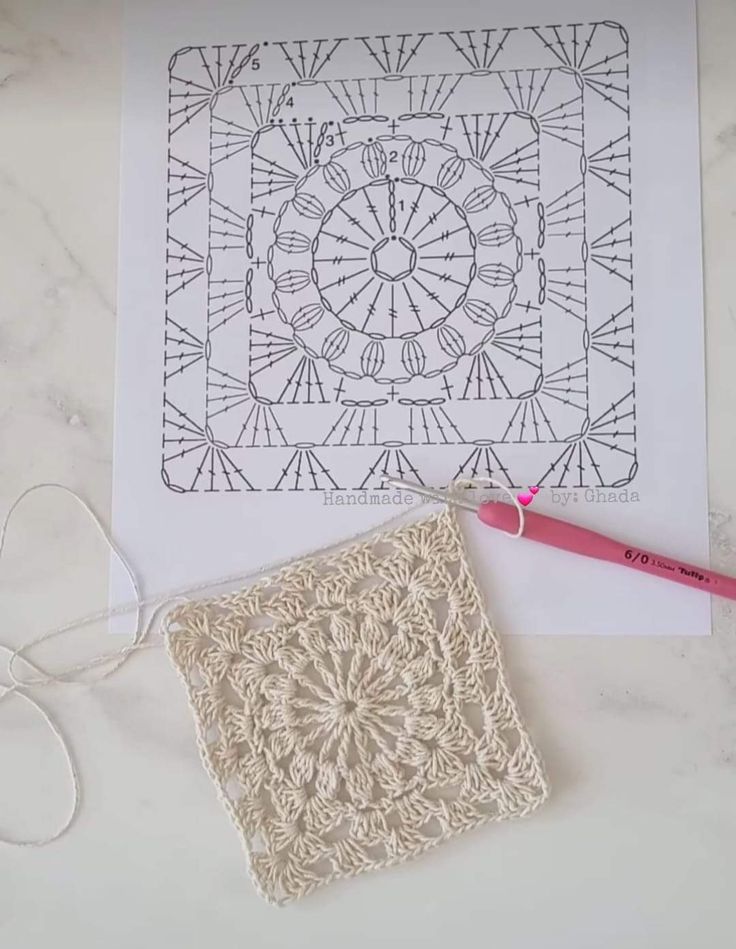 a crochet doily next to a piece of paper and scissors on a table