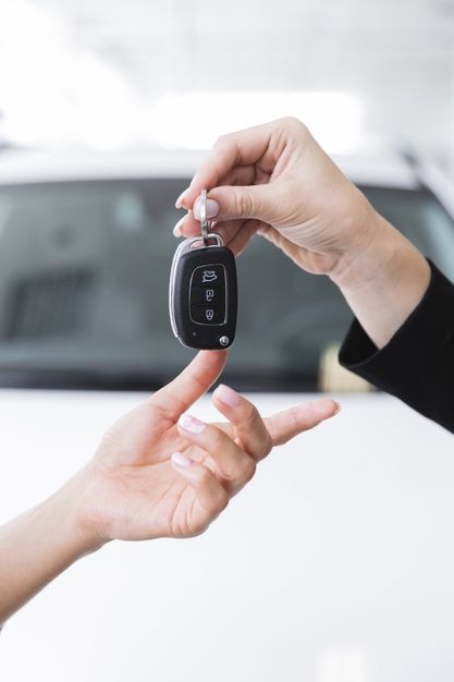 two people exchanging keys to each other in front of a car