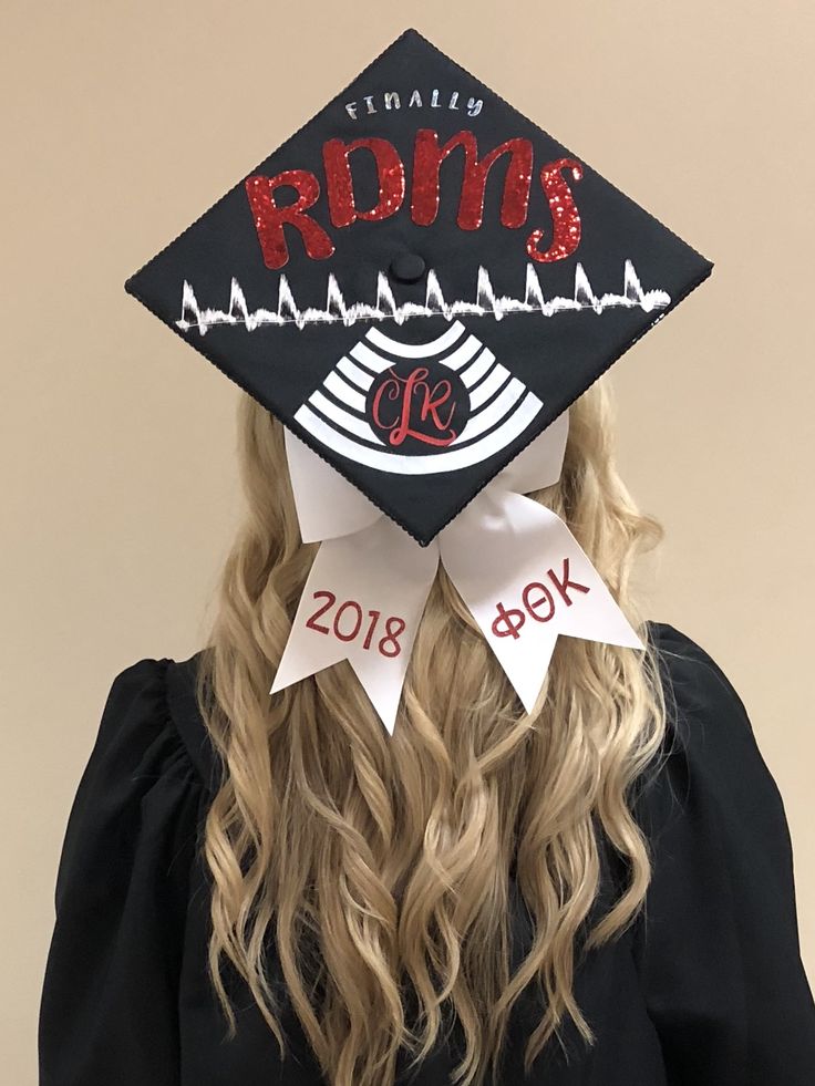 a woman wearing a black graduation cap with red letters on the front and white ribbon around her neck