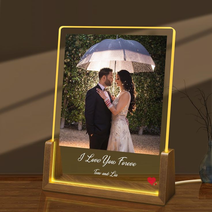 a couple standing under an umbrella in front of a photo frame with the words i love you forever written on it