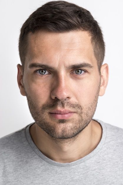 a close up of a person wearing a gray shirt and looking at the camera with a serious look on his face